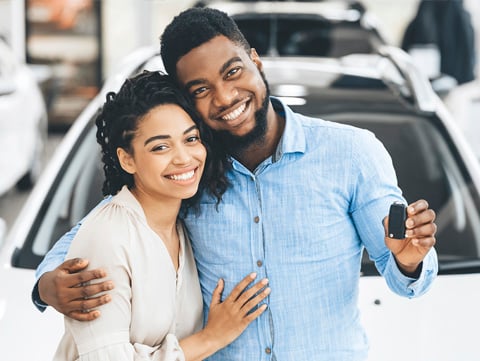 African American man and woman. Man is holding up keys to a new car.