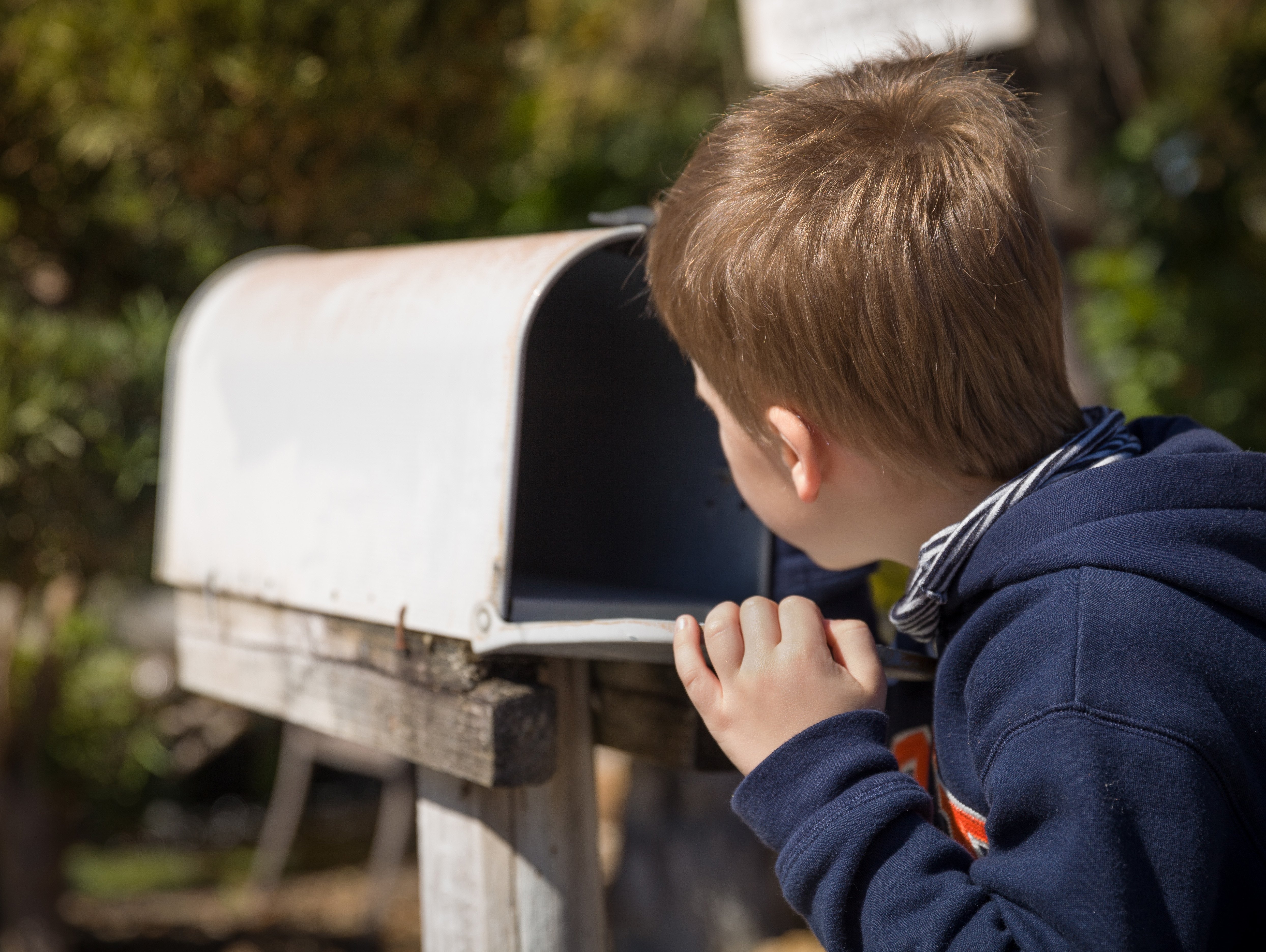 Young boy looking into a mail box to see if he has mail