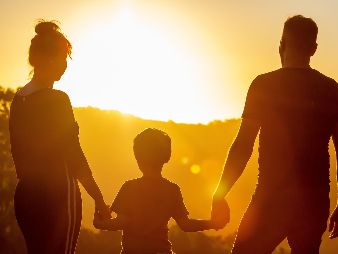 Family holding hands at sunrise